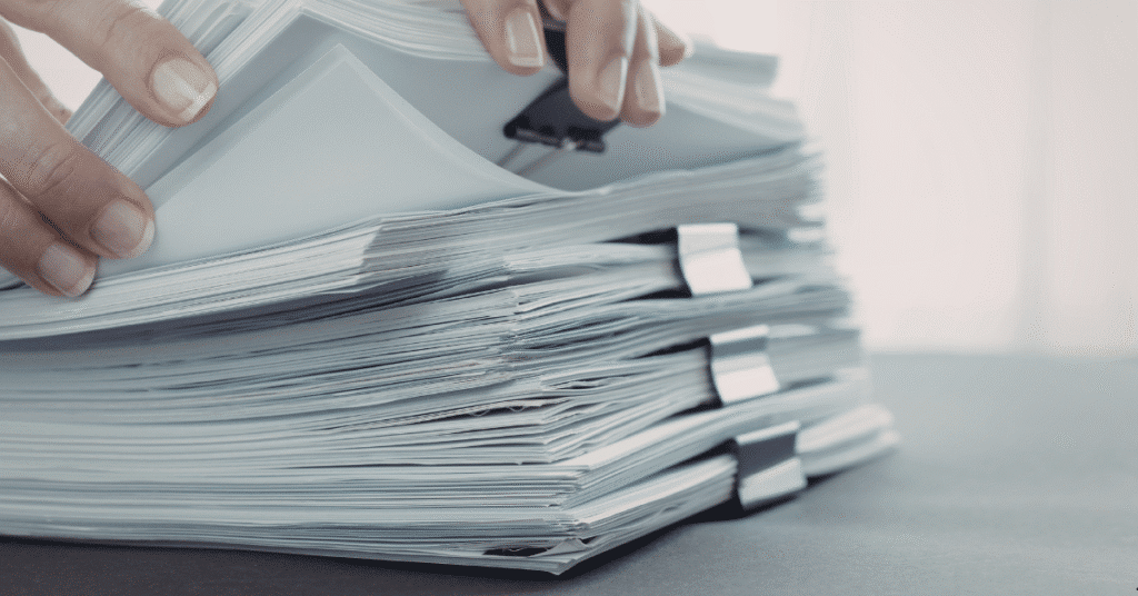 a credit union representative thumbing through stacks of paperwork, stressing the importance of a strong document management software